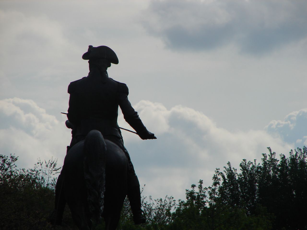 a man on a horse in silhouette on a cloudy day