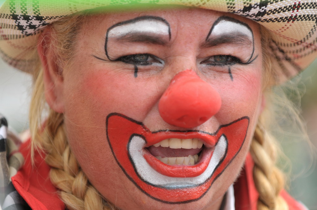 a smiling clown with painted face and ids