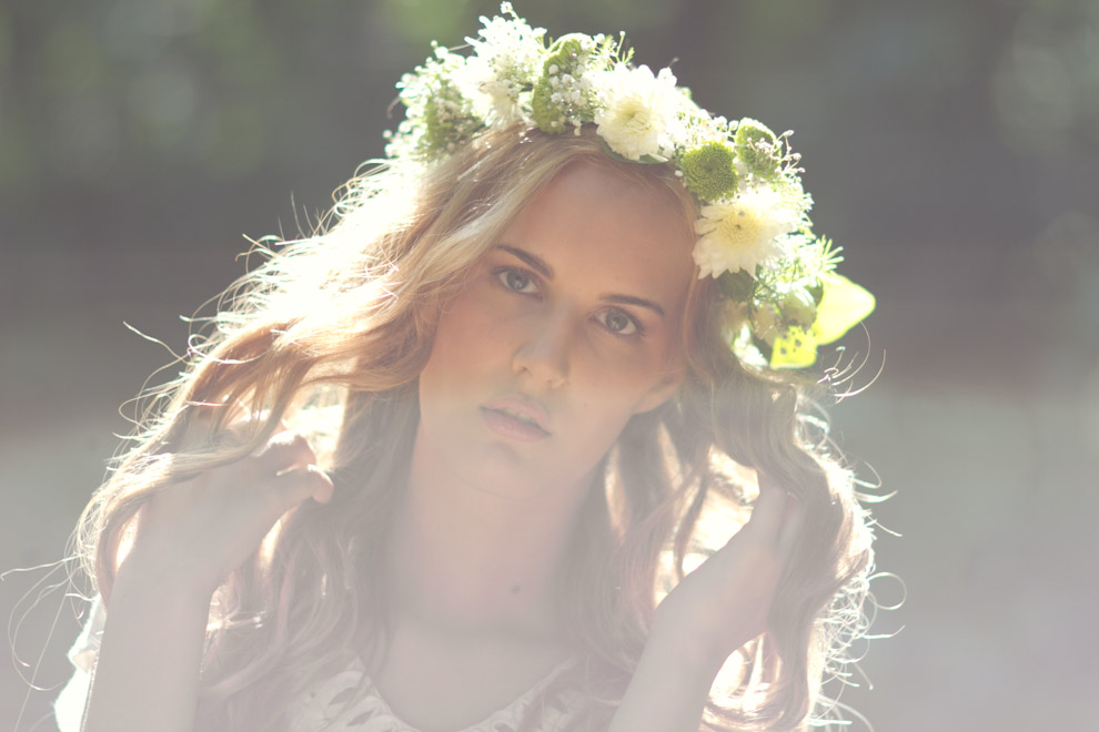 woman with flowery wreath of green and white flowers posing