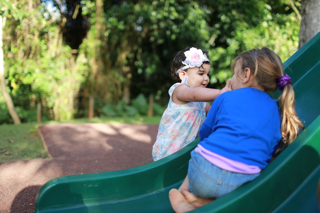 two little girls on a slide looking at each other
