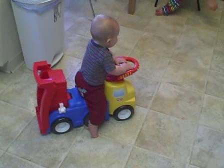 a baby playing with a plastic toy truck