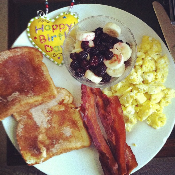 the breakfast plate is full of bacon, toast, and eggs