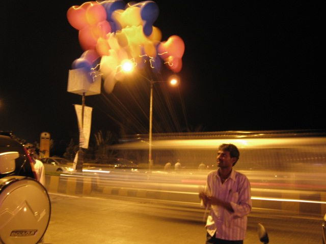 a man riding a motorcycle with some bright balloons flying in the air