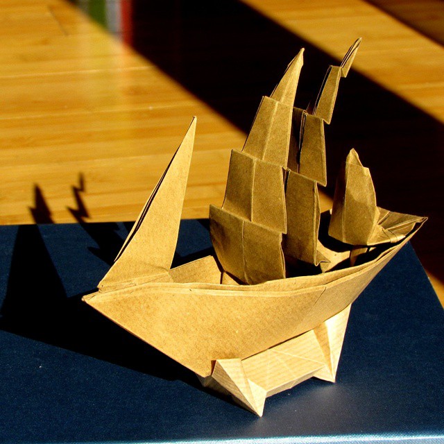 a folded origami sailboat on a wooden floor