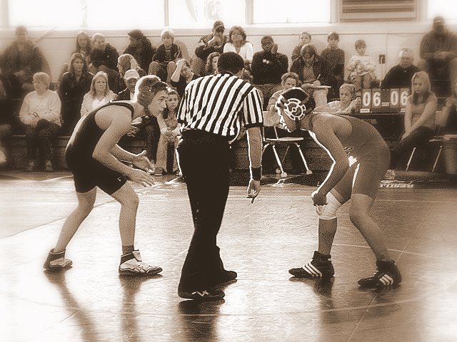 an image of wrestling match with referee watching