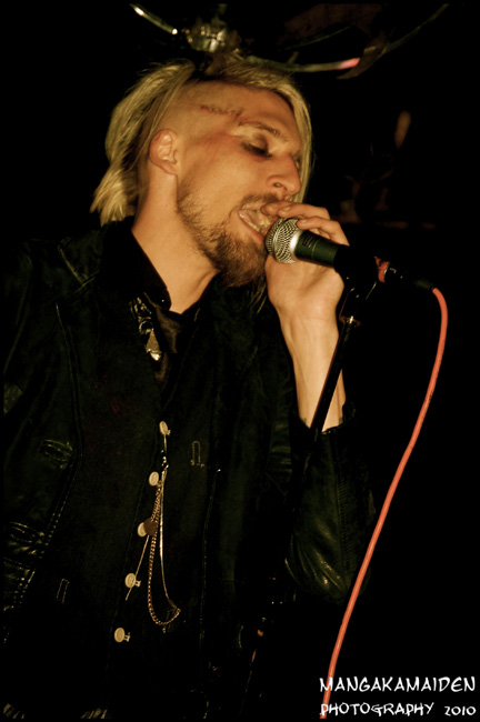 a man with blonde hair and piercings singing into a microphone