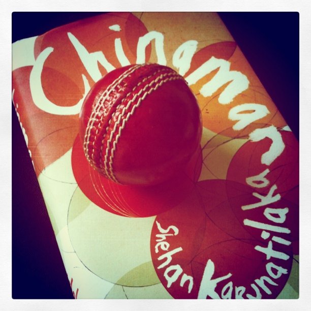 a red cricket ball sits on a chinese tartan