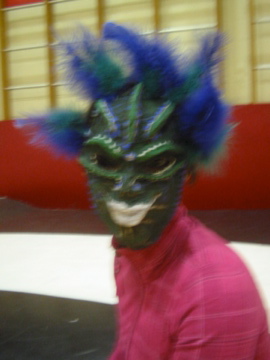 a man in pink is wearing a mask with blue feathers