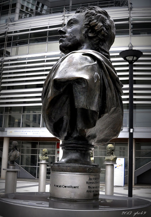 a statue of a man with a cloak is in front of an office building