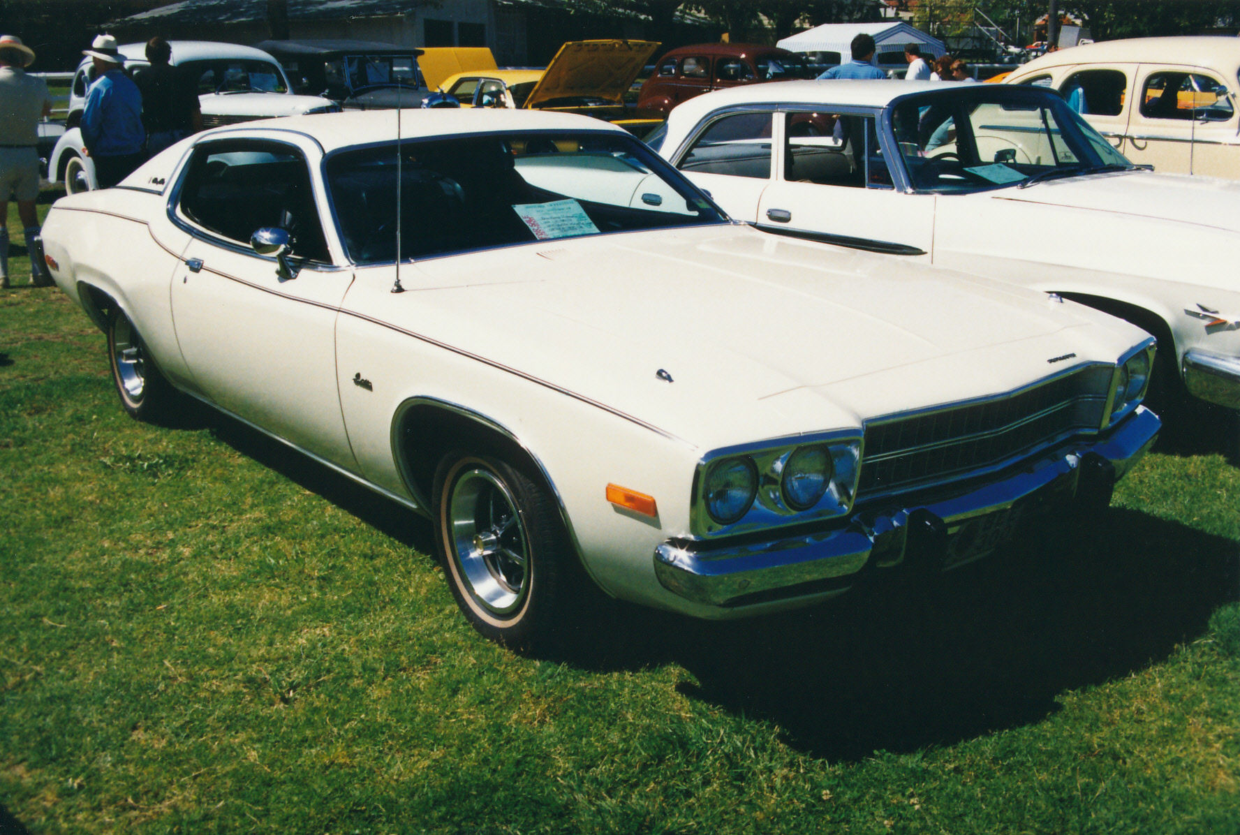 two white cars sitting next to each other in the grass