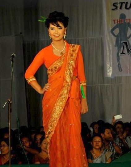 an indian woman in orange dress standing on stage