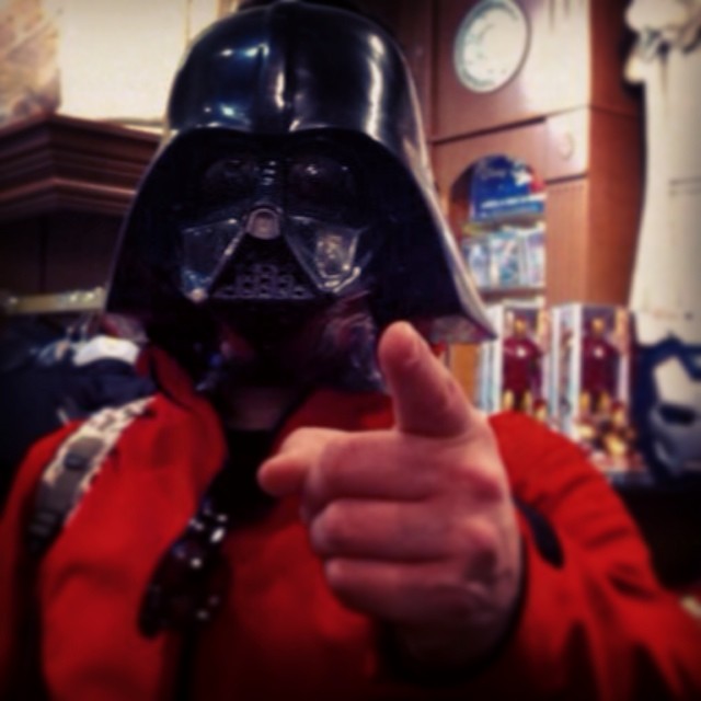 a person wearing a darth vader helmet gives the thumbs up sign