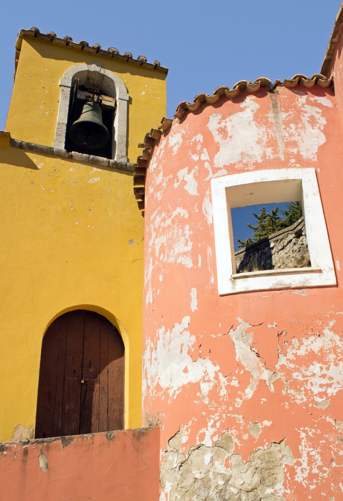 a yellow building with a bell in the window