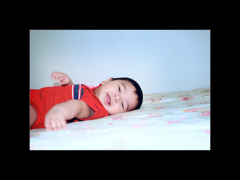 a child smiles while laying on a bed
