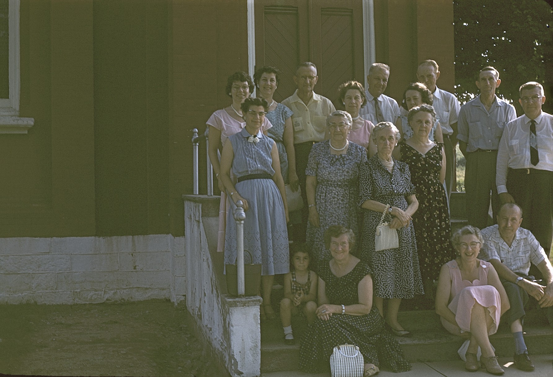 a group of people standing and sitting outside of a house