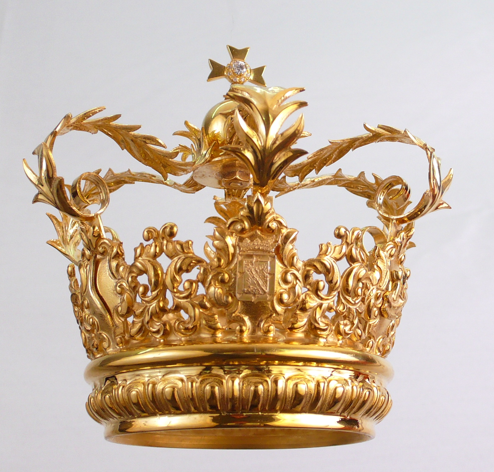 a golden crown with leaf designs is suspended from the ceiling