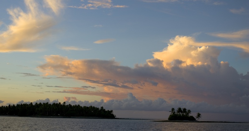 an island is in the distance with two smaller islands at sunset