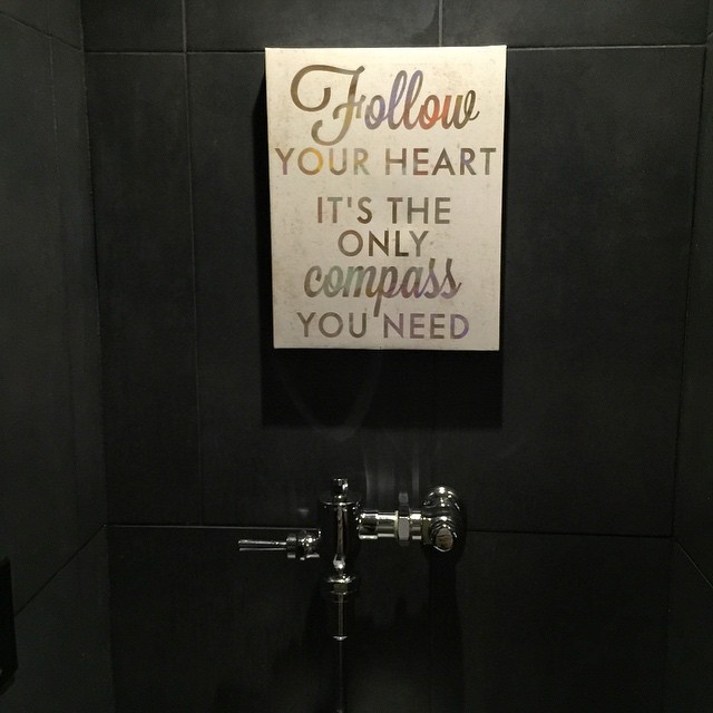 bathroom stall with black tiled wall and sign