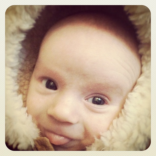 a baby in a coat smiling into the camera