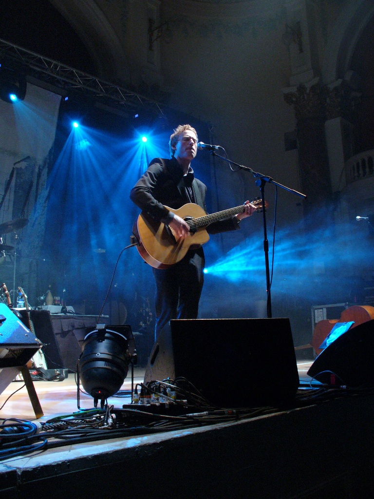 a man playing a guitar on a stage with blue lights