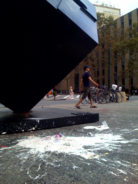 a man walking past a big sculpture