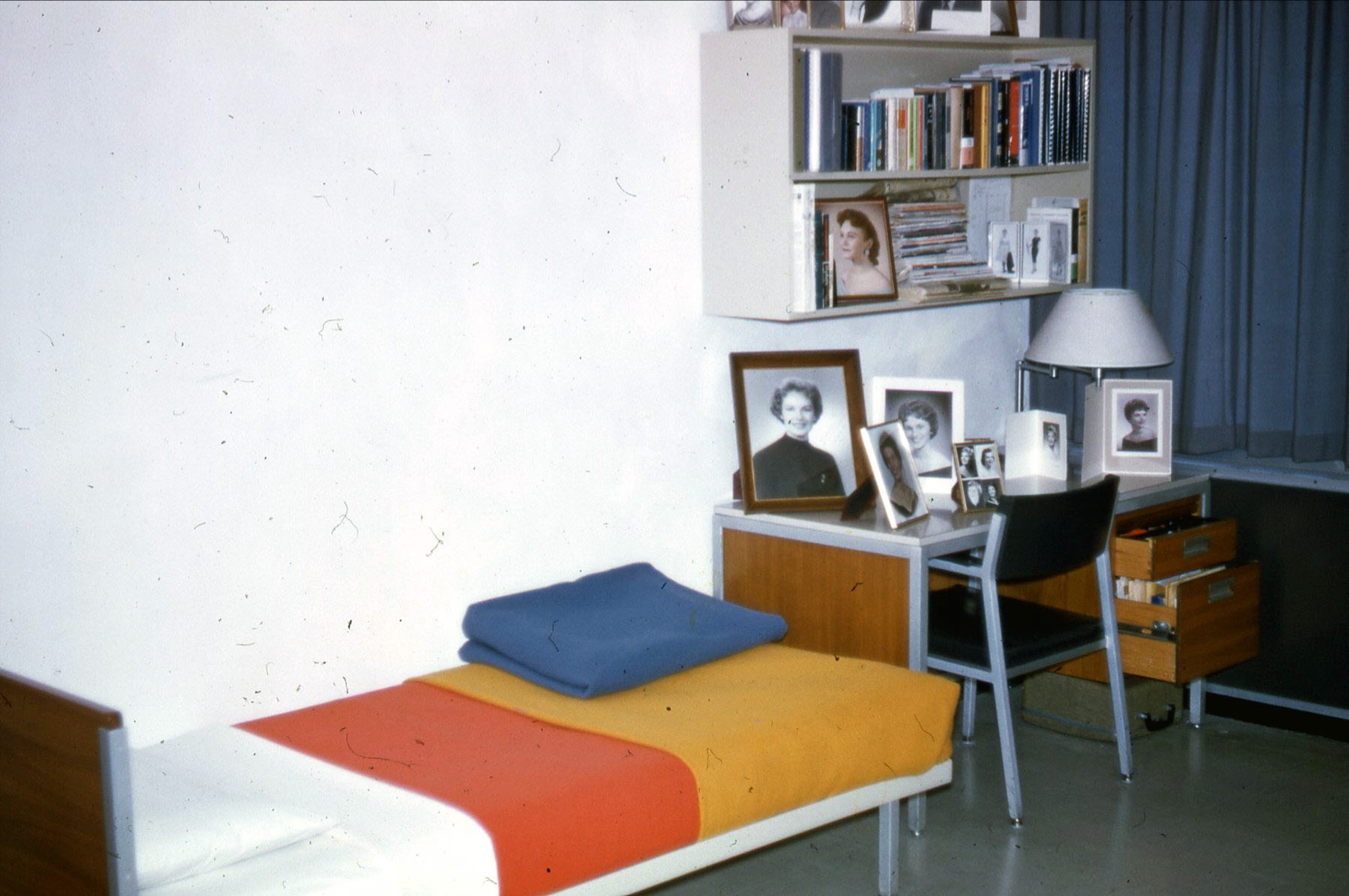 a bedroom with a desk with several pictures on the wall
