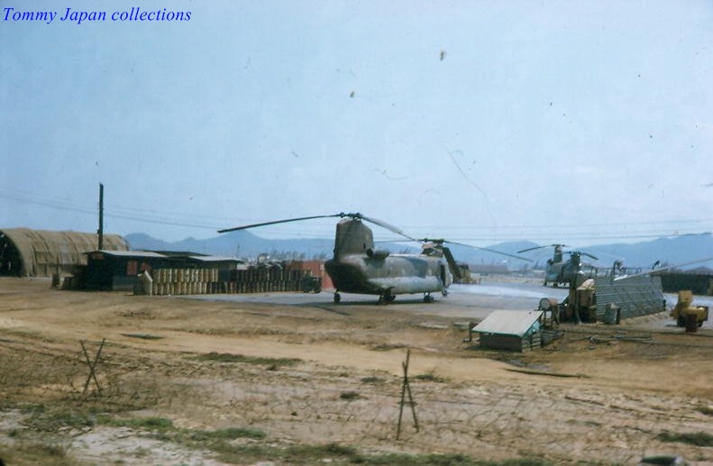 military helicopter landing on runway with military vehicles nearby