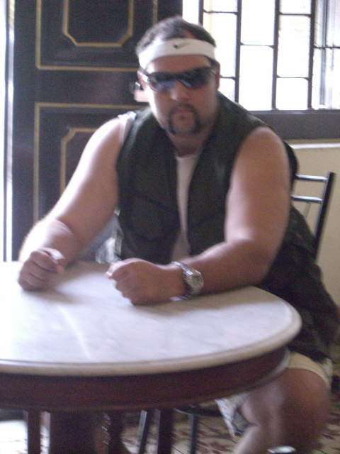 a man sitting at a table in sunglasses and leather vest