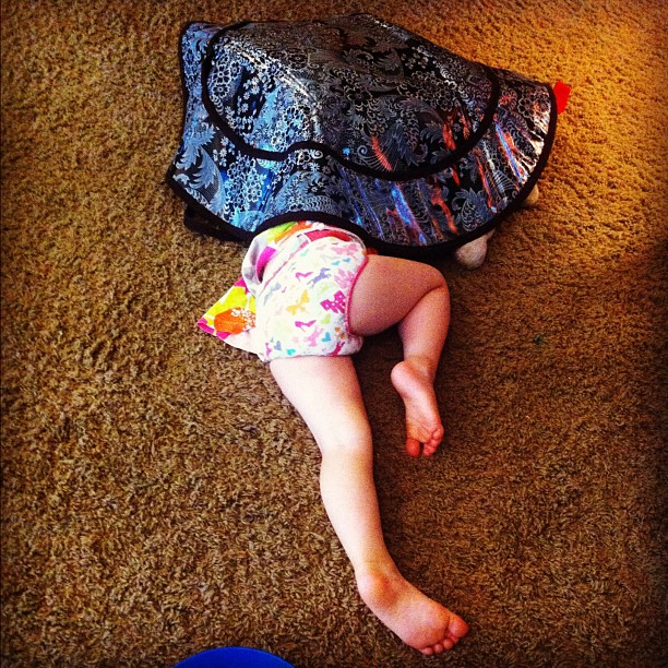 the young child is laying on the floor near an umbrella