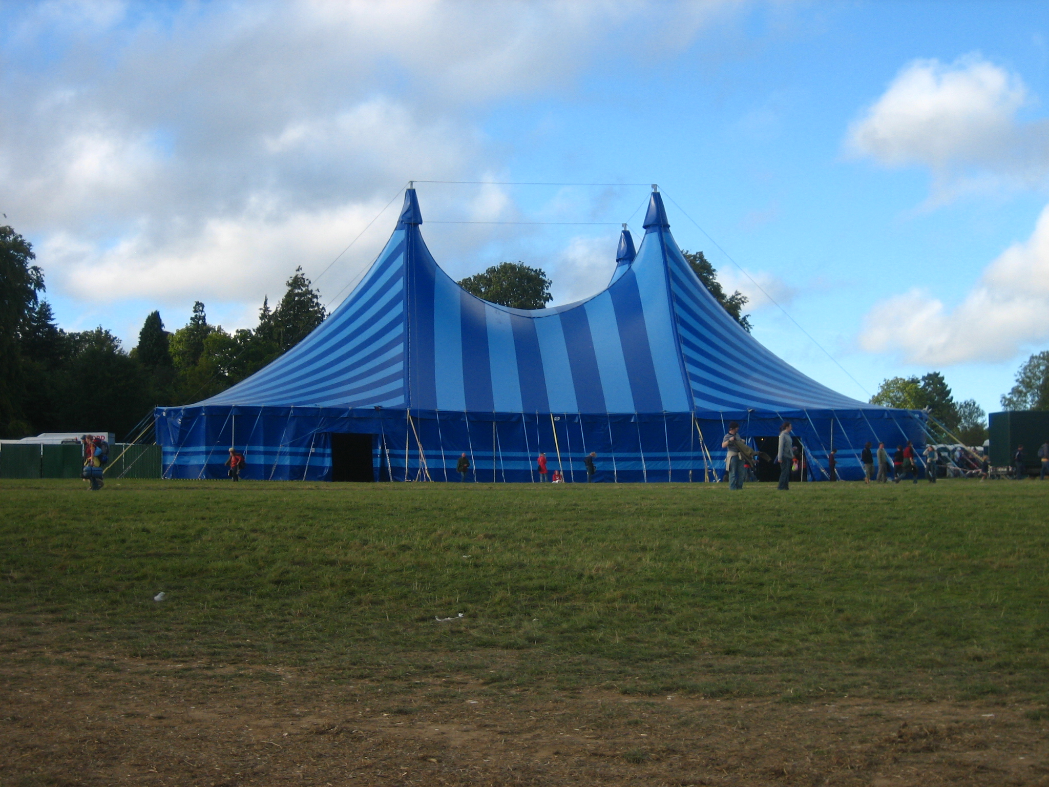 a blue and white tent sits outside in the grass