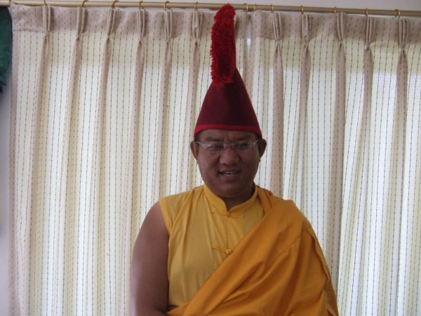 a person in a yellow monk outfit with a red knitted hat