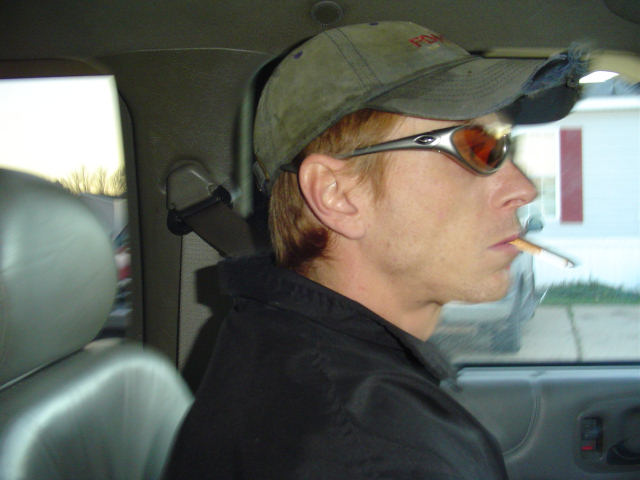 a man wearing sunglasses and hat smoking in the backseat