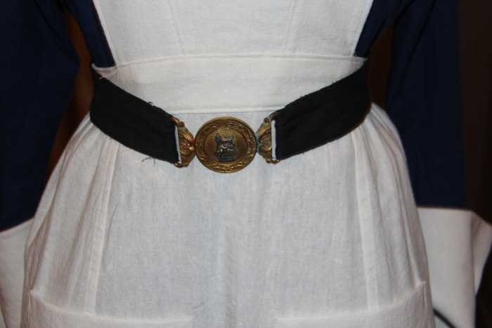 a white dress with a black sash and a gold on