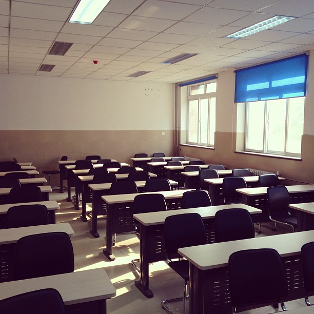 the empty classroom has black tables and chairs