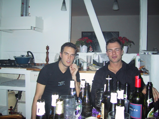 two men standing next to table full of bottles of wine