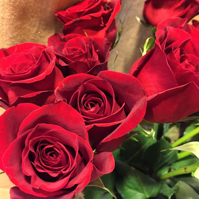 a large bunch of red roses sitting on the table