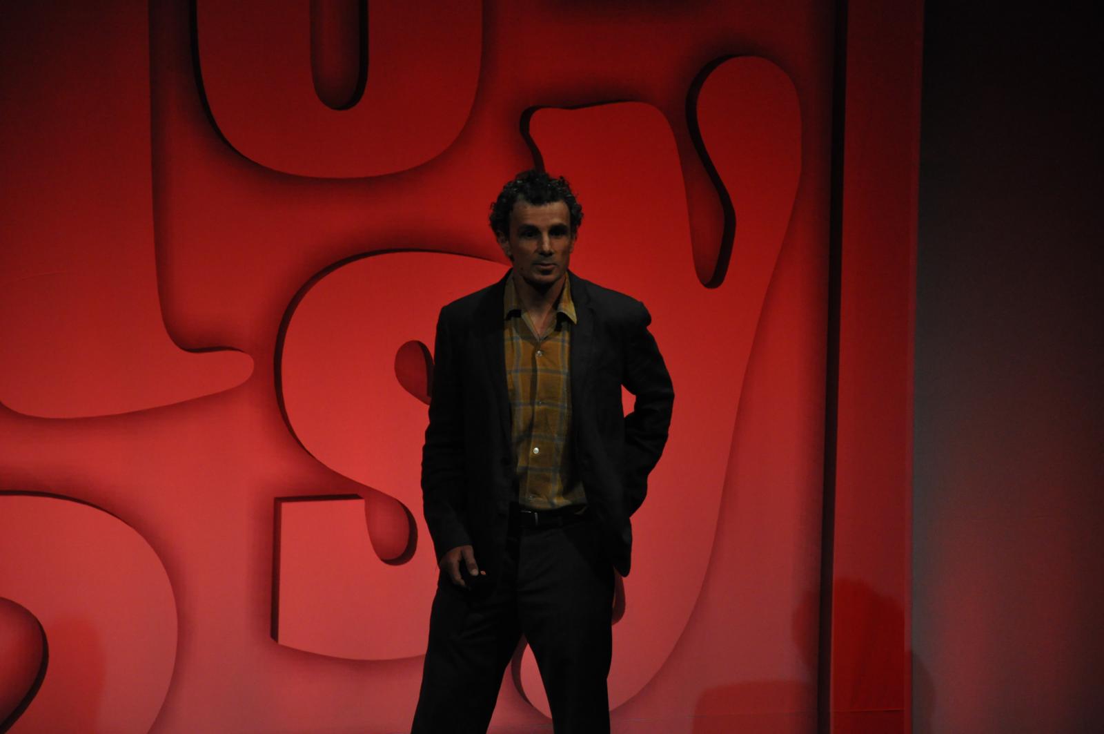 a man standing on the runway, in front of a red background