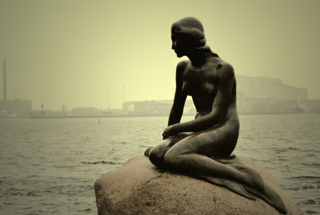 a statue sits on a rock overlooking the ocean
