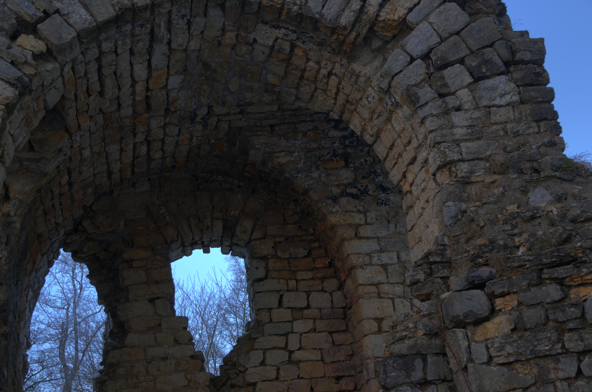 an arch in a stone wall with trees