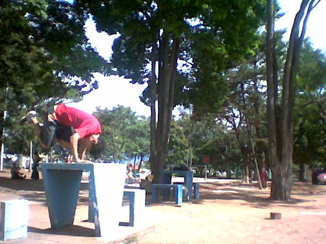 a man doing skateboard tricks on an outdoor park bench