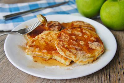 a white plate topped with pancakes next to green apples