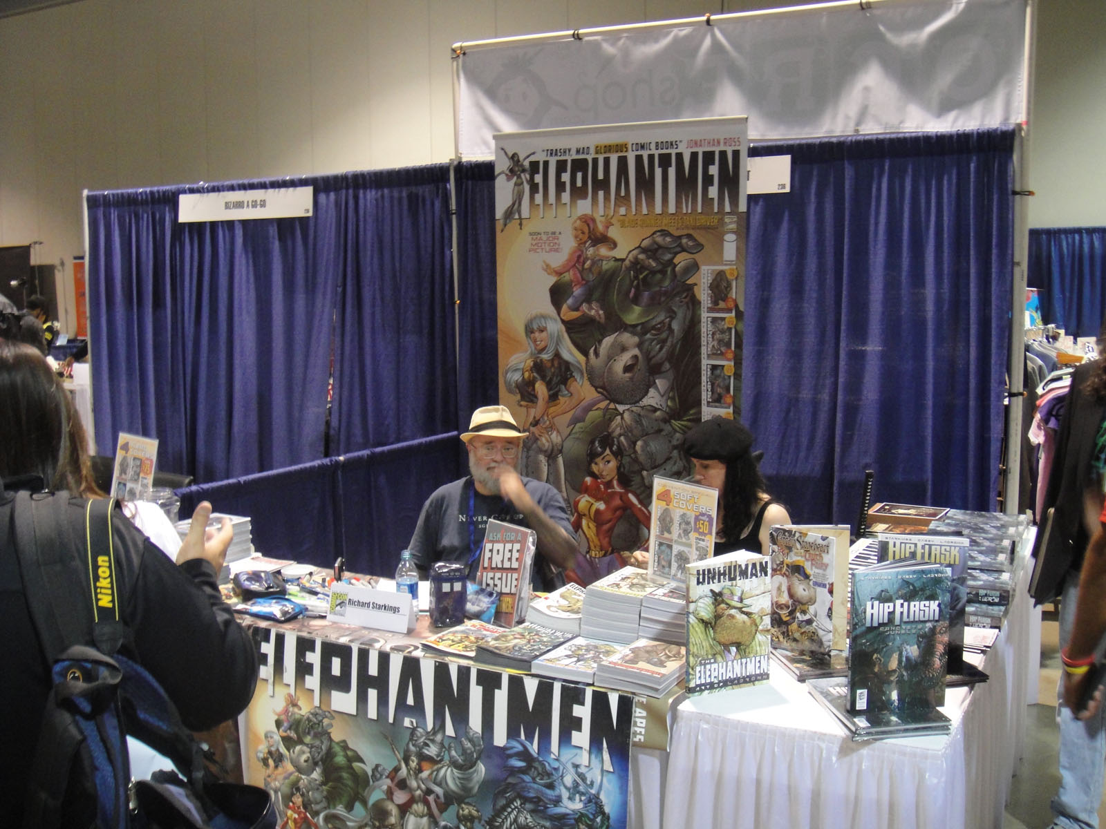 a man stands behind a table covered with comic books