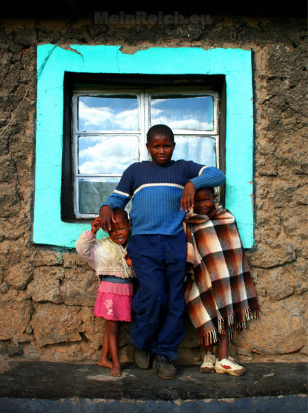a young man standing with two small girls next to his window