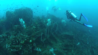 scubars are swimming over an underwater sunken ship