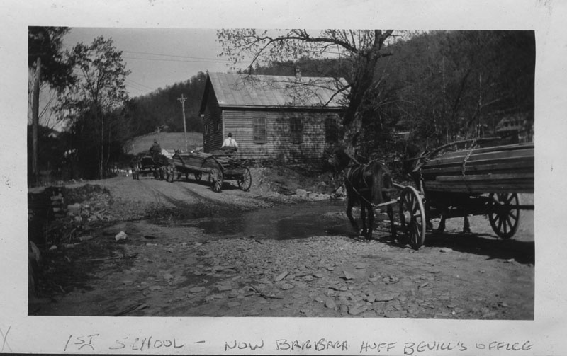 an old black and white po with two men next to horses pulling wagons