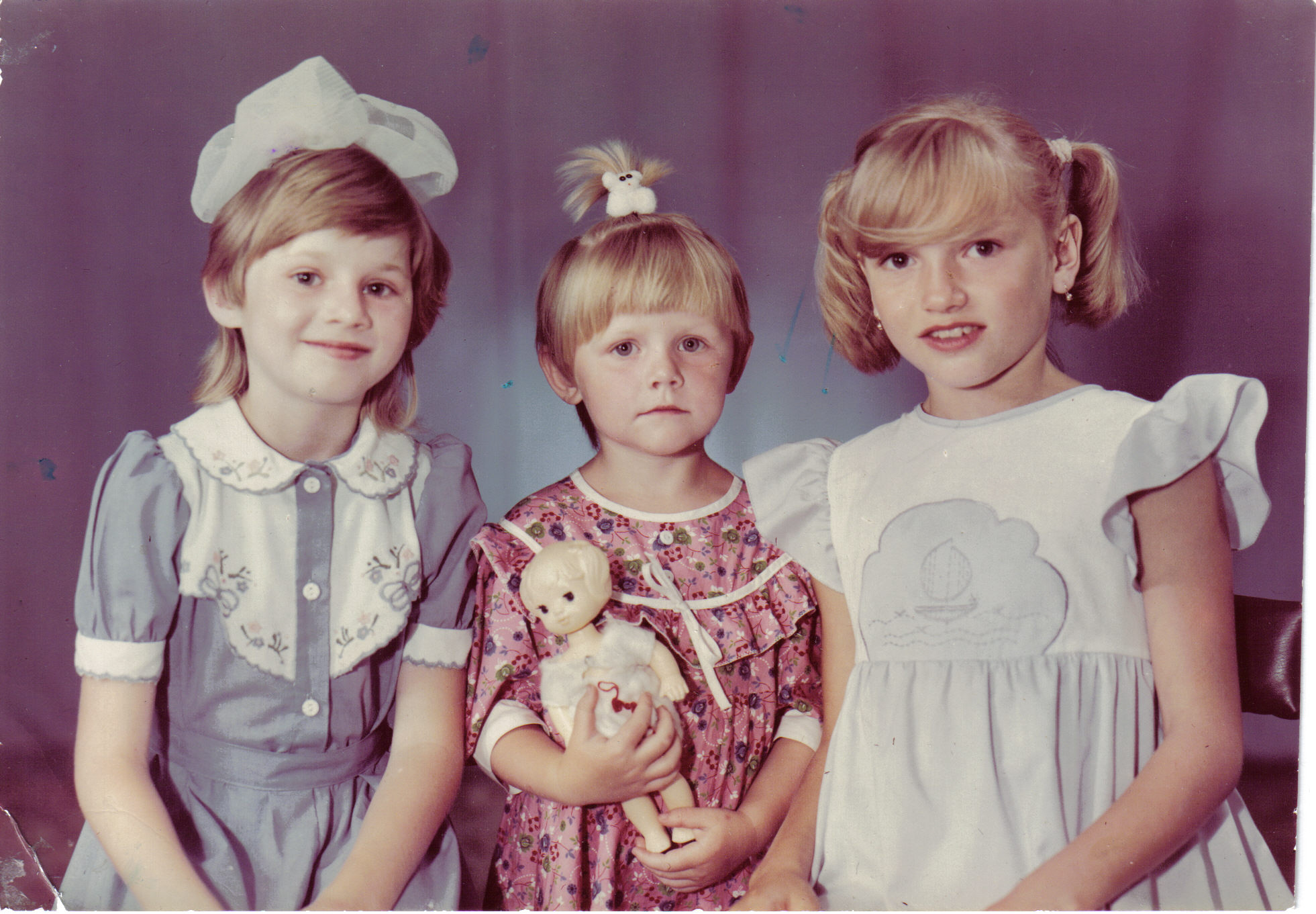 three girls dressed in matching clothing are standing side by side