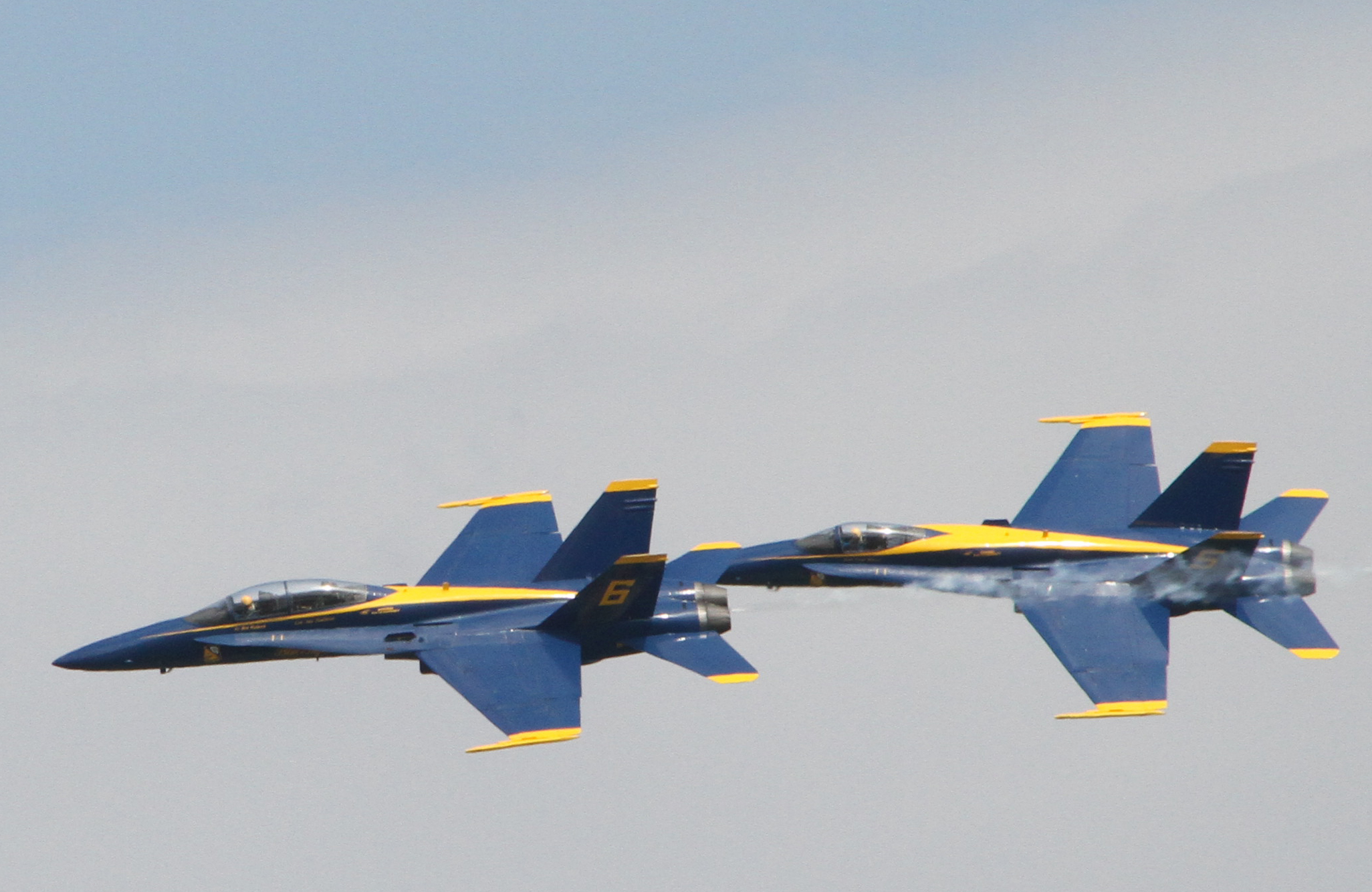 two blue and yellow military jets fly together