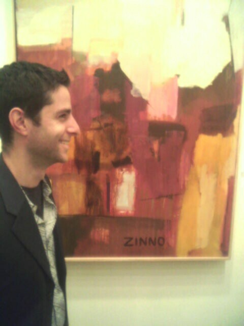 a man standing next to a painting on a wall