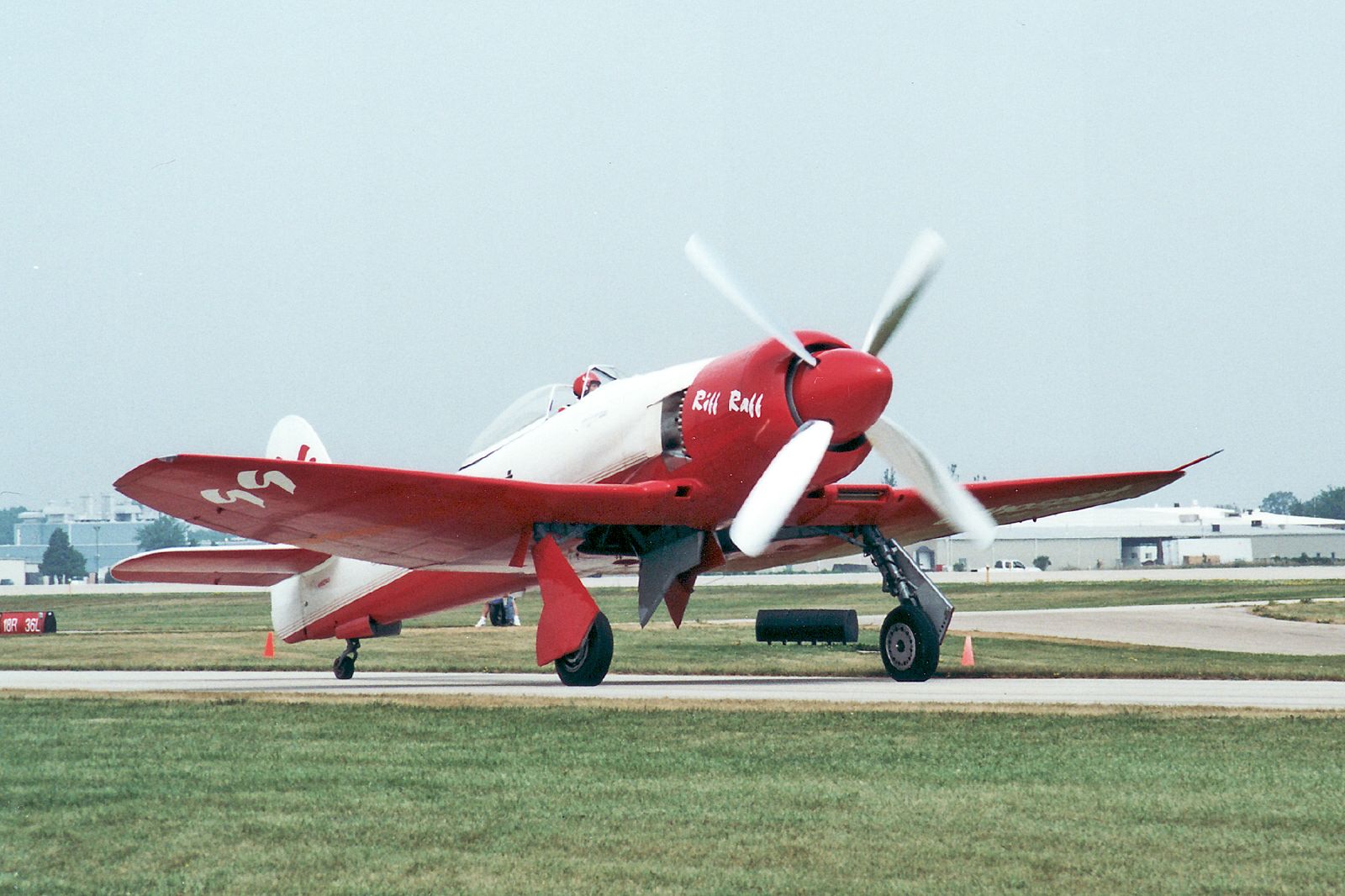 red and white plane at an airport with grass