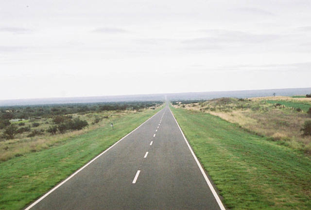 a long road running across a lush green field